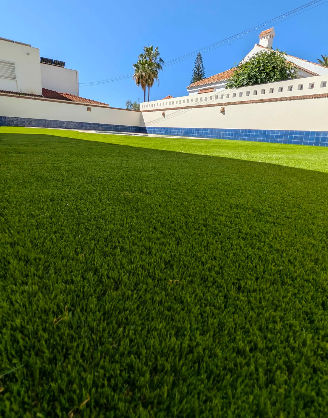 Césped artificial de cerca junto a un muro blanco, trabajo de Sector Natura