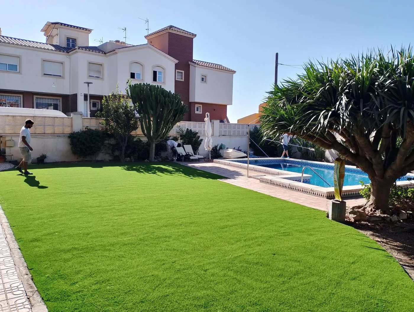 Jardín con césped artificial recién instalado junto a una piscina, trabajo de Sector Natura