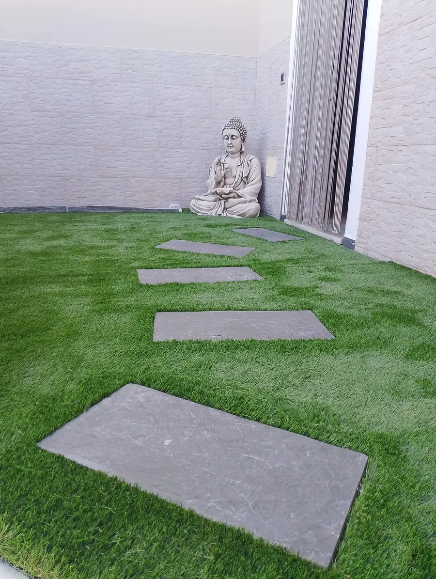 Patio con césped artificial y pasos de piedra, trabajo de Sector Natura