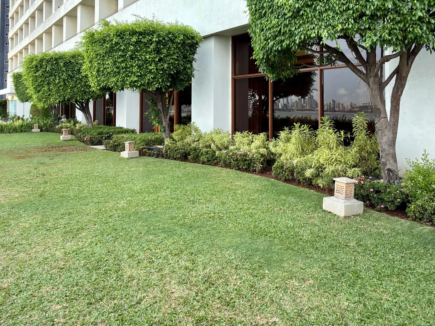 Zona verde de un edificio de viviendas con césped, setos y árboles recortados