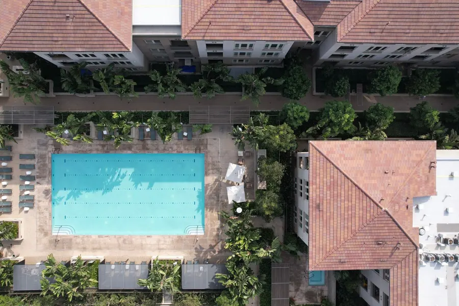 Patio interior de un residencial con piscina y jardín, visto desde arriba