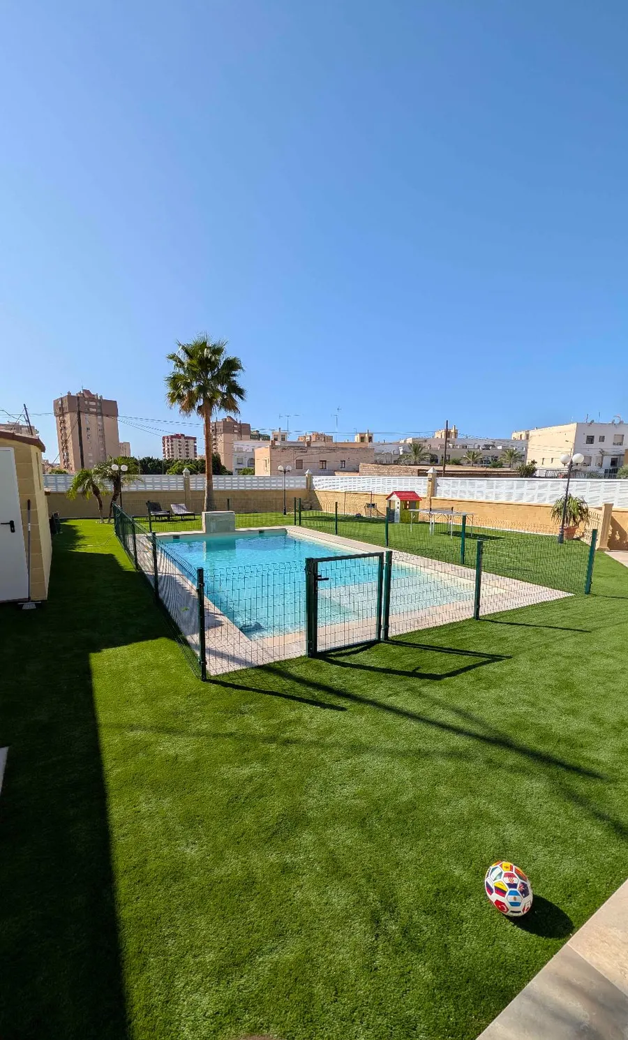 Zona de piscina de una vivienda con césped artificial y vallado