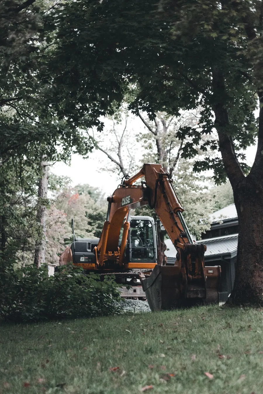 Excavadora trabajando en un jardín entre árboles