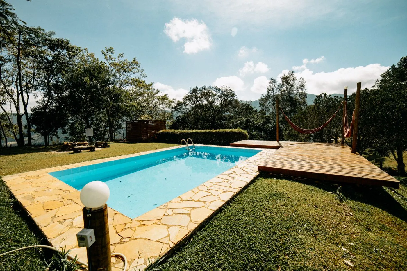 Piscina rectangular de fibra junto a una tarima de madera y césped