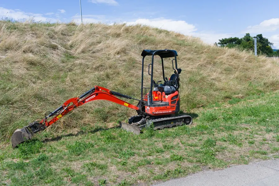 Miniexcavadora preparando el terreno en una parcela con césped