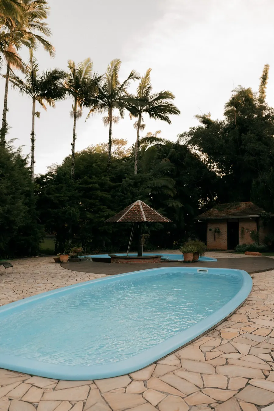 Piscina ovalada de fibra azul rodeada de suelo de piedra